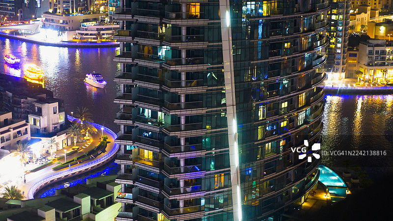 迪拜码头 - 滨水运河上灯火辉煌的塔楼和明亮倒影的生动城市夜景。图片素材