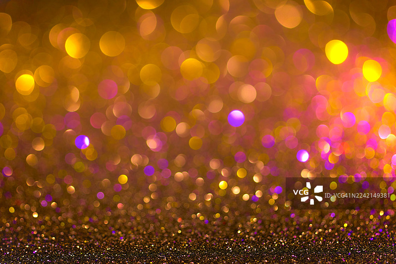金色闪光散景背景，色彩柔和的灯光，带有柔和的紫色和粉色光晕，营造节日气氛图片素材