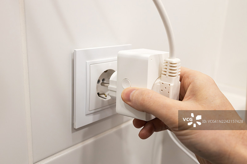 男人的手将智能插头插入电源插座图片素材