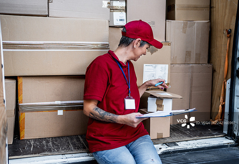 送货女郎在卡车内检查包裹图片素材