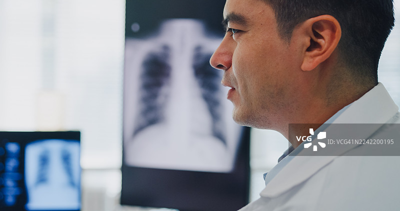在诊室里，一名成年男性医生在咨询期间向年轻女性患者解释肺部X光片结果。医疗保健概念。图片素材