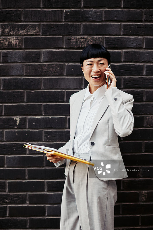户外办公：女子在通话中，手持文件夹图片素材