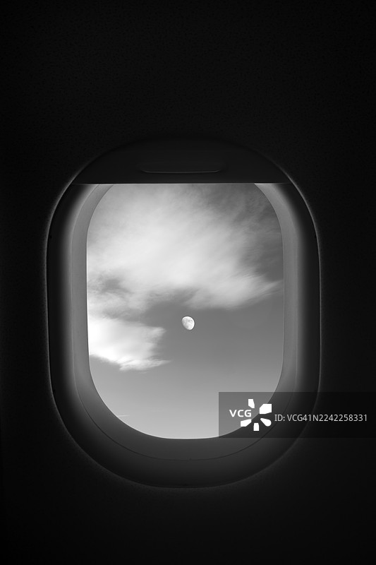 飞机窗外的乘客视角，天空中的月亮，单色调图片素材