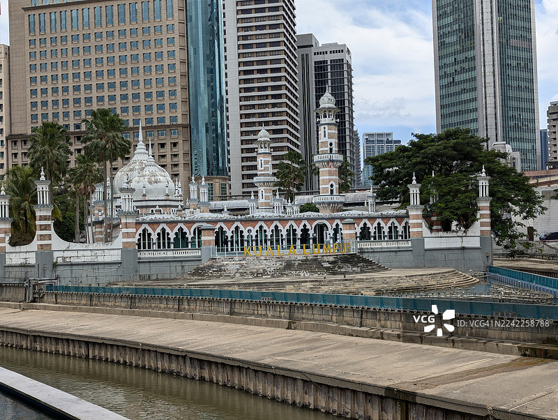 马来西亚吉隆坡，加美清真寺与现代摩天大楼沿着巴生河畔图片素材