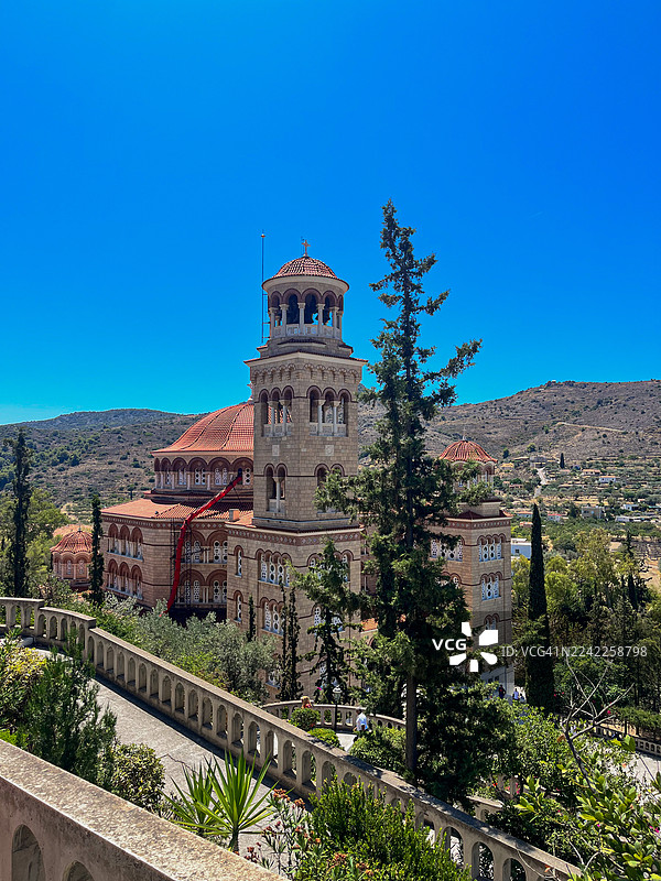 希腊埃伊纳岛，一座雄伟的修道院在晴朗的蓝天下俯瞰着山谷图片素材