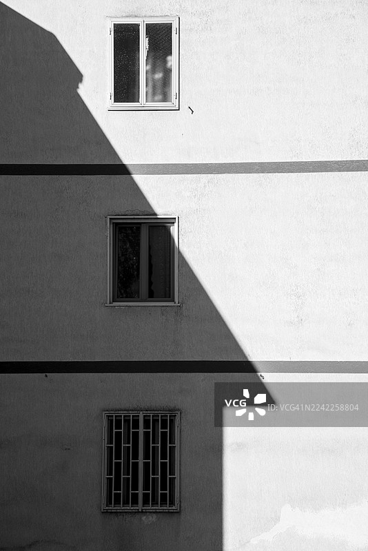 抽象的黑白建筑细节，展示了带有窗户和强烈阴影的建筑外观图片素材