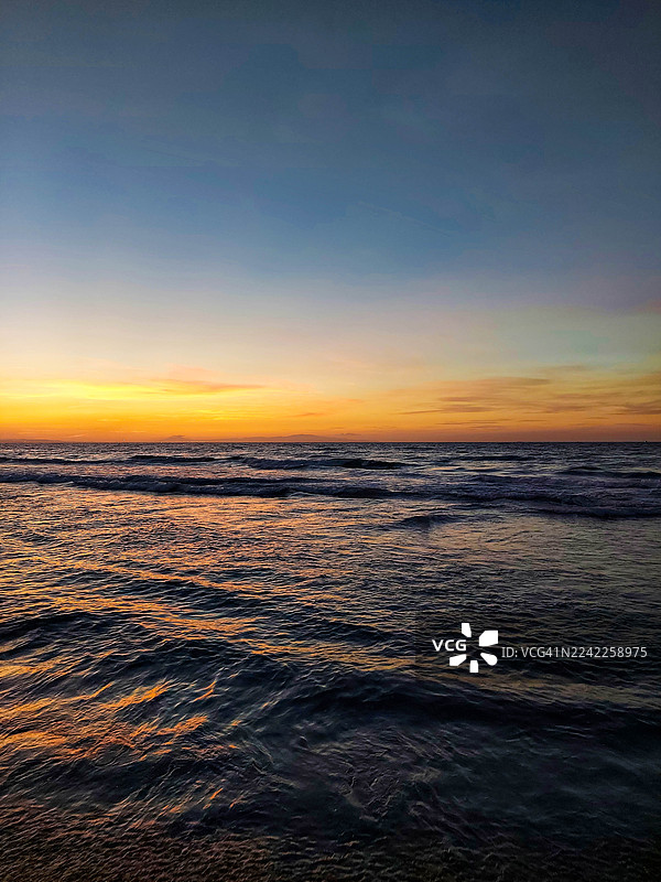 夕阳下，海面映衬着充满活力的天空，风景如画图片素材