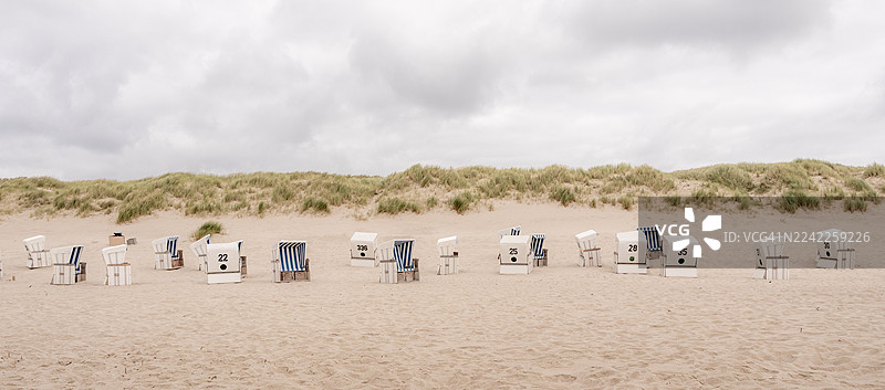 阴天下的沙滩，有海边的椅子和长满草的沙丘，德国的叙尔特岛图片素材