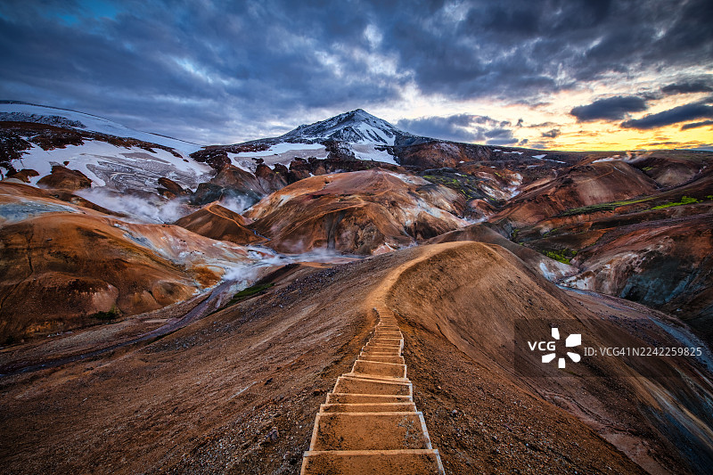 冰岛凯尔丁加费特尔（Kerlingarfjöll）色彩斑斓的地热景观上，壮丽的日落映照着蜿蜒小径，通向远方的雪山。图片素材