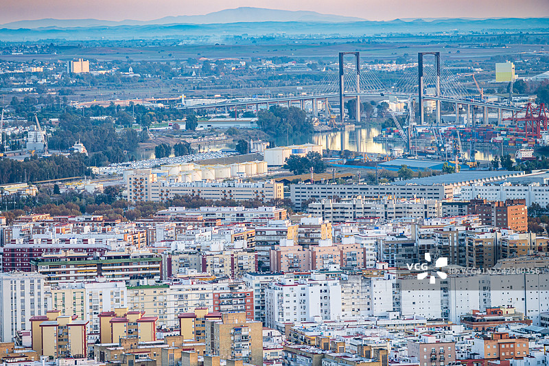 日落时分，现代斜拉桥横跨河流，俯瞰着广阔的城市景观，展示了城市发展与自然风光，西班牙塞维利亚。图片素材