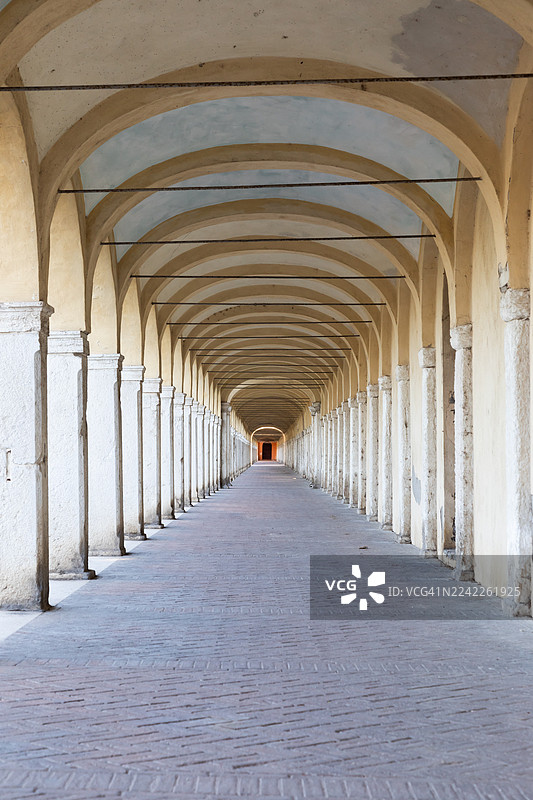 意大利一座古老建筑的长拱形走廊，通向远方的光线，营造出深度和透视感图片素材