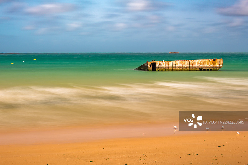 法国，蓝天下的海中，一座混凝土块的宁静海滩长曝光照片图片素材