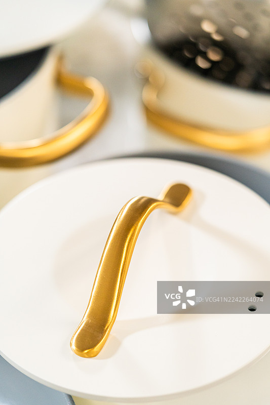 特写镜头下，白色厨具上优雅的金色把手，展现出现代设计和浅景深效果图片素材