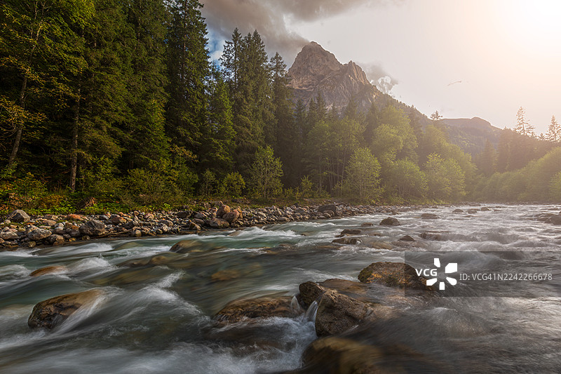 瑞士劳伦斯冰川峡谷（Schattenhalb, Switzerland）的风景，一条河流穿过森林，远方有山峦和戏剧性的天空。图片素材