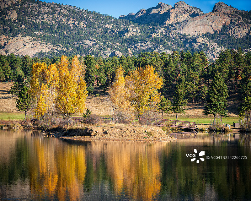 秋日绚烂色彩倒映在宁静的湖面上，背景是远处的山峦，位于美国埃斯蒂斯公园。图片素材
