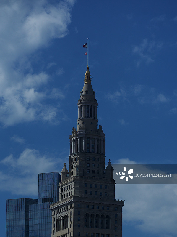 低角度拍摄的古老摩天大楼，背景是现代建筑，天空多云呈蓝色，地点：美国克利夫兰，地标：联合车站大楼图片素材