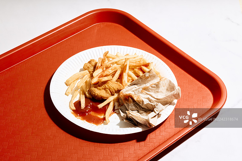 一个托盘，上面放着炸薯条、鸡块、番茄酱和一张餐巾纸图片素材