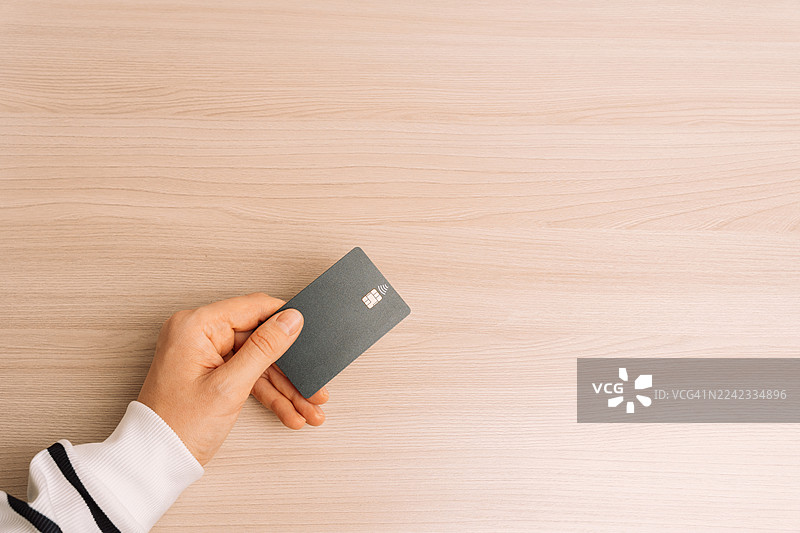 手持非接触式卡片放在木桌上图片素材