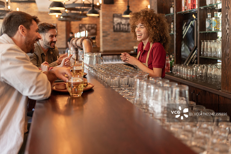 酒保在当地酒吧与常客开怀大笑图片素材
