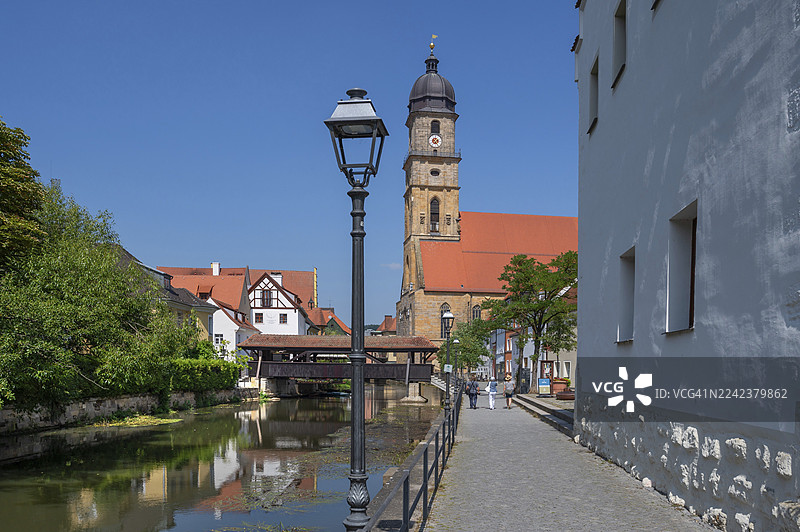 在菲尔斯河畔散步，背景是安贝格、上普法尔茨、巴伐利亚、德国的施夫布吕克和圣马丁教堂图片素材