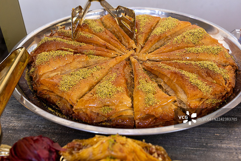 金属托盘上展示着土耳其开心果果仁蜜饼圆环，旁边放着公用夹子图片素材