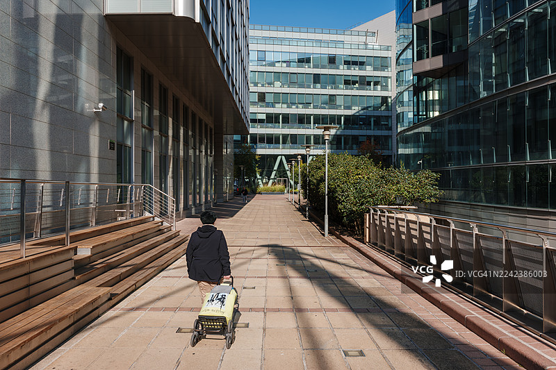 一个人推着行李车走过现代化的拉德芳斯步行街图片素材