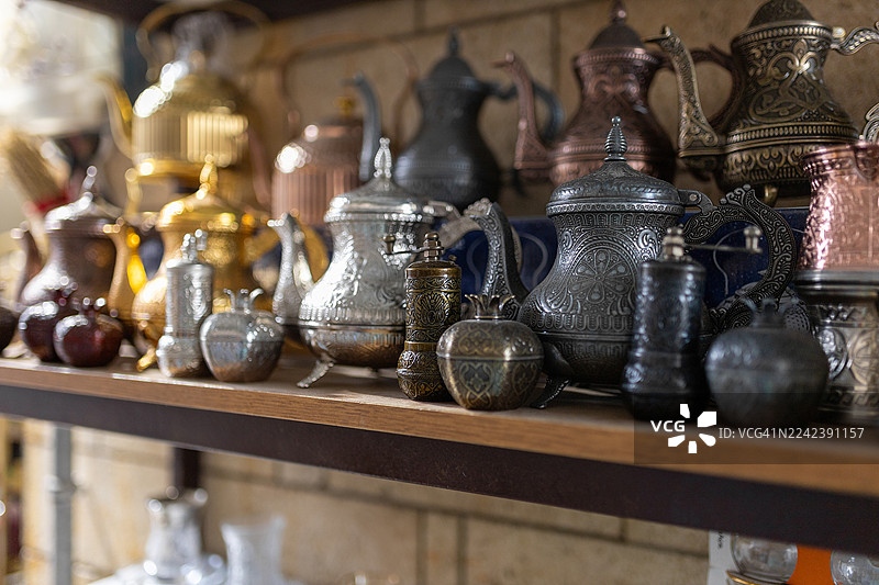 工艺品店的木架上陈列着华丽的金属茶壶和器皿图片素材