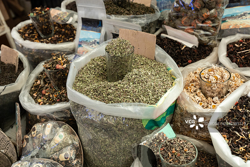 市场摊位上展示的各种大包装干香草和茶饮混合物图片素材