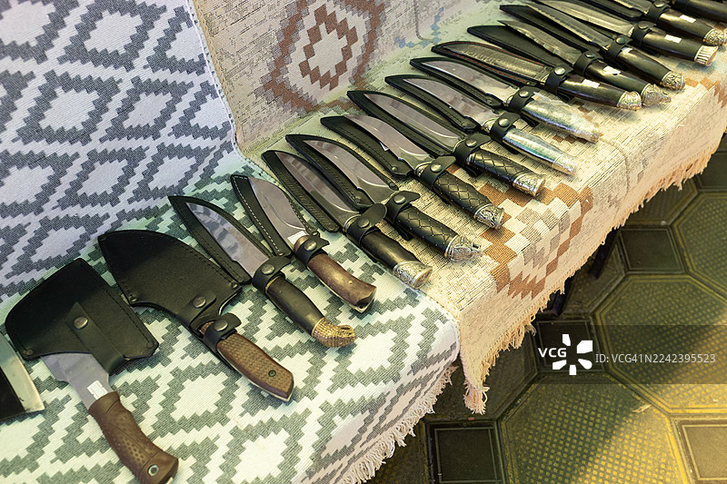 各种直刀整齐地排列在有图案的毯子上，用于展示和销售图片素材