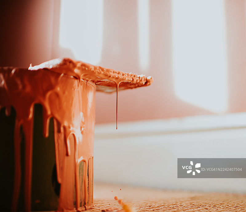 油漆罐特写，刷子上沾有滴落的油漆，刷子放在罐子顶部图片素材