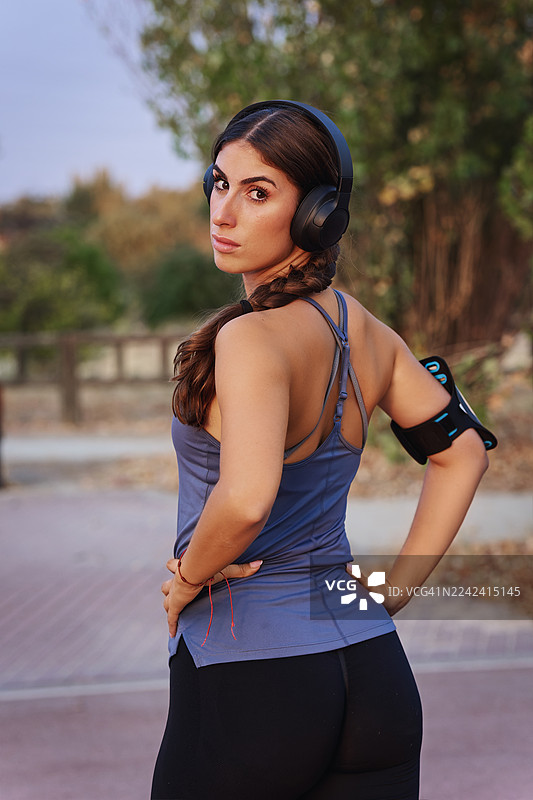 公园里，一位戴着耳机、眼神挑衅的运动风女性肖像图片素材