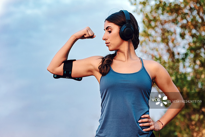 一位女运动员在户外骄傲而坚定地展示着她的肱二头肌图片素材