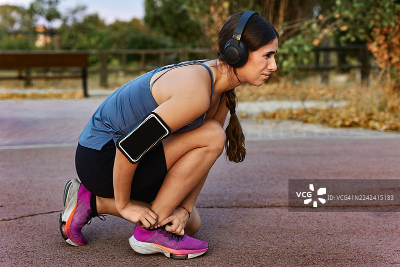 年轻女子在户外跑步前系鞋带图片素材