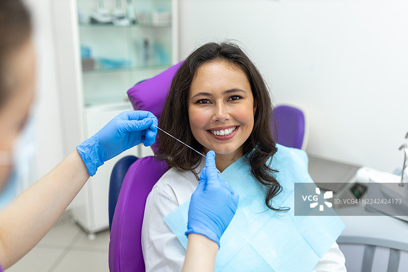 一名快乐的患者在例行检查中，由牙医坐在牙科椅上，面带微笑。图片素材