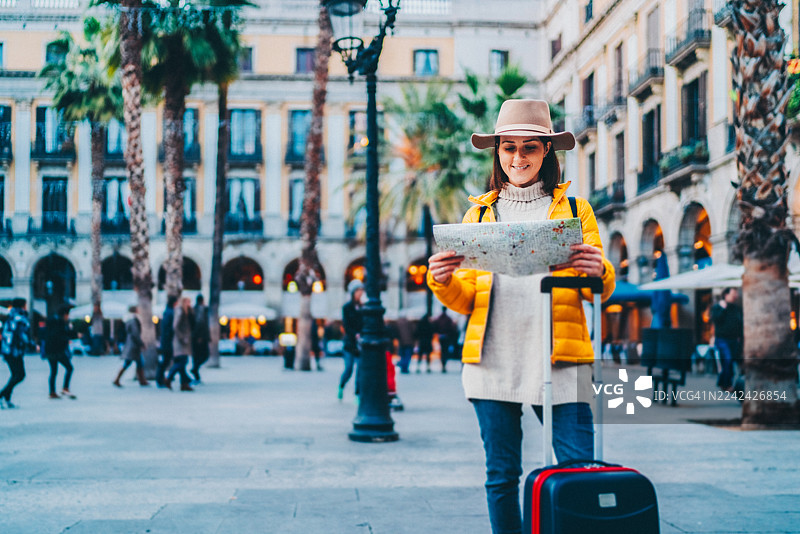 一位女性游客在巴塞罗那市中心的广场上阅读地图图片素材