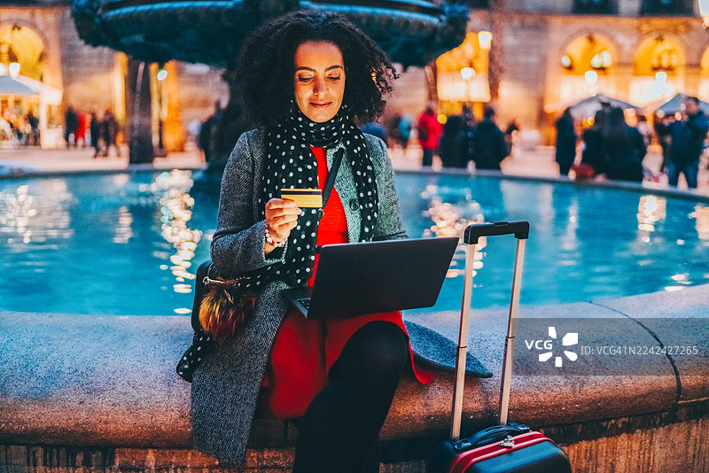 一名旅行者在巴塞罗那的喷泉旁，最后一刻用笔记本电脑预订酒店图片素材