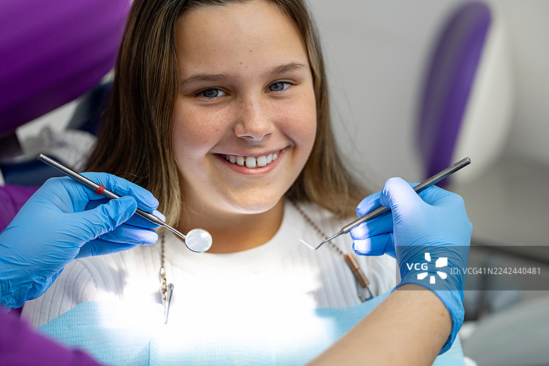 年轻快乐的患者在牙医诊所，医护人员戴着手套，准备好牙科器械进行检查。图片素材