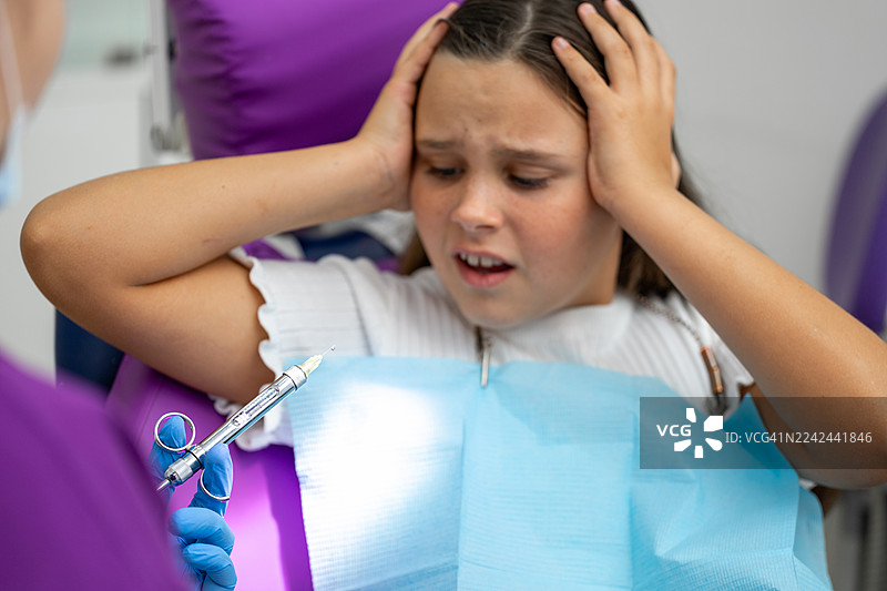 年轻的患者在牙科手术中感到焦虑，护士正在诊所里准备注射器图片素材