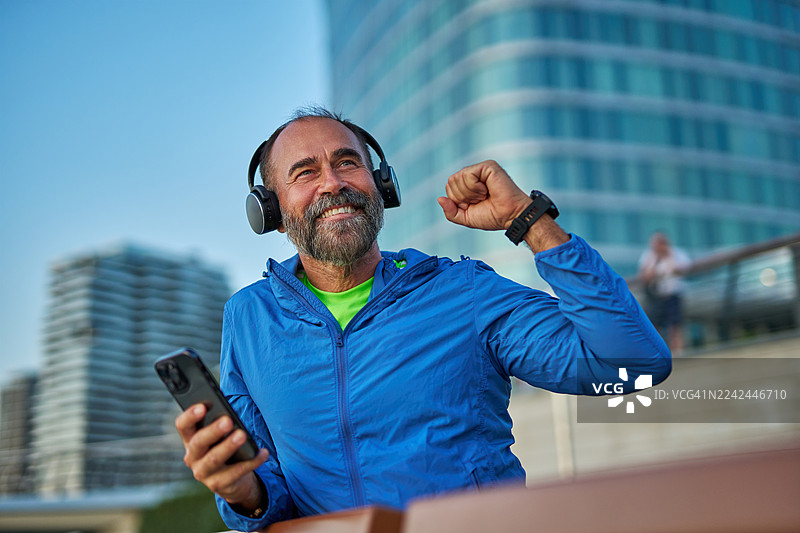 戴着耳机和智能手机的年长男子在户外锻炼图片素材
