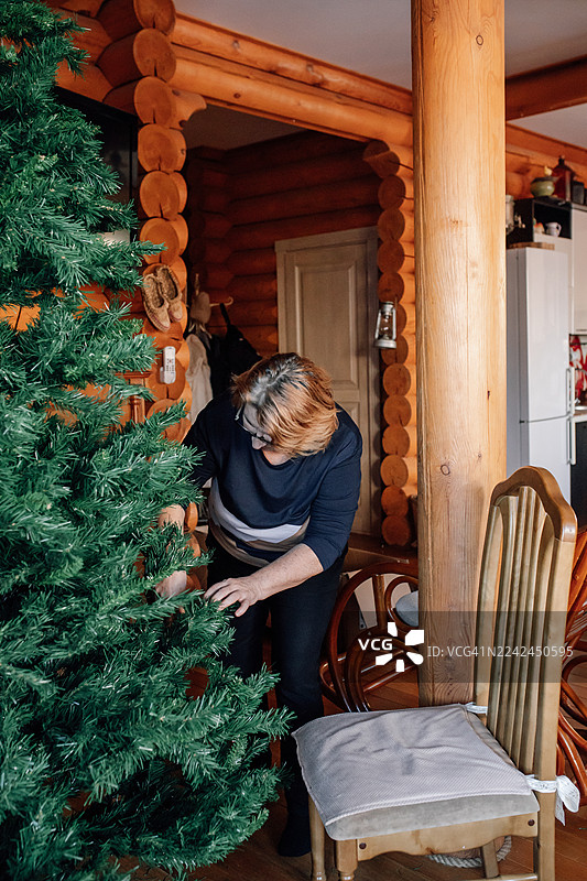 一个人在舒适的木屋室内装饰圣诞树图片素材