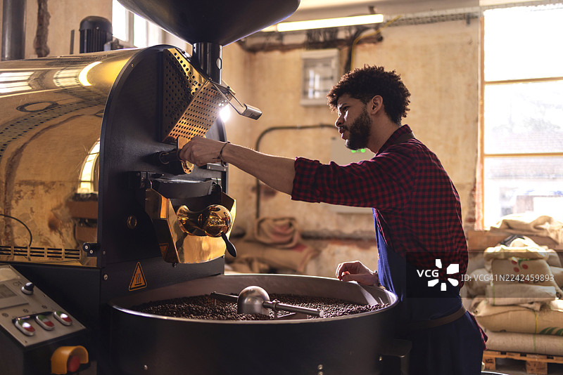 咖啡师在舒适的咖啡馆里使用工业烘焙机烘焙咖啡豆图片素材