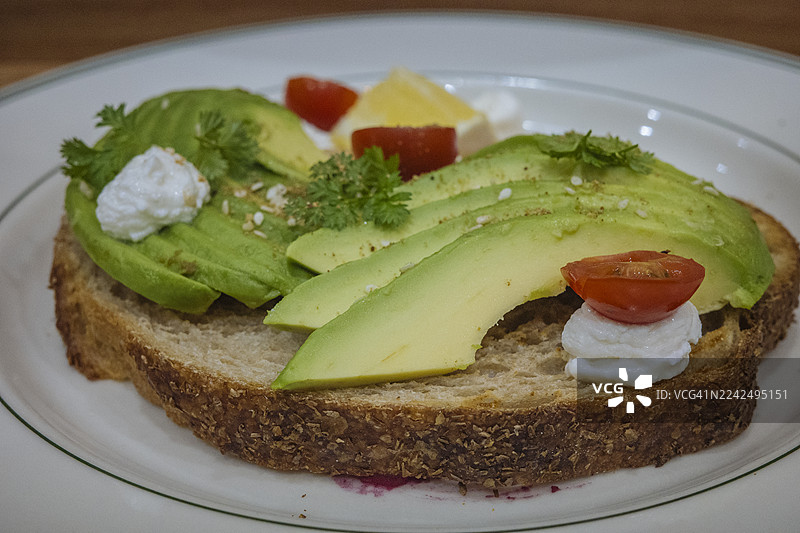 吐司上放着牛油果片，上面点缀着番茄和菲达奶酪图片素材