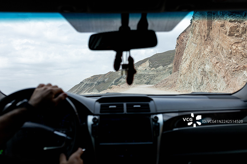 从车内看到的驾驶视角，车辆正沿着悬崖边的崎岖山路行驶图片素材