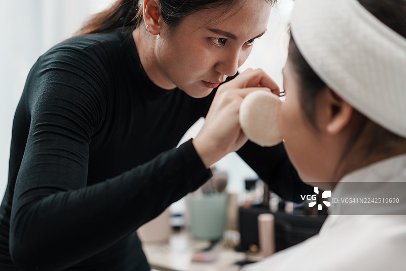 亚洲化妆师在新娘婚礼准备过程中，专注于眼影细节的涂抹，展现其在工作室的专业技能和美容护理职业素养。图片素材