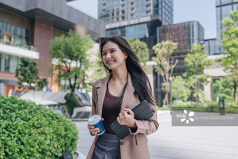 自信解放的女商人在大城市里行走，一位女士拿着手机的肖像图片素材