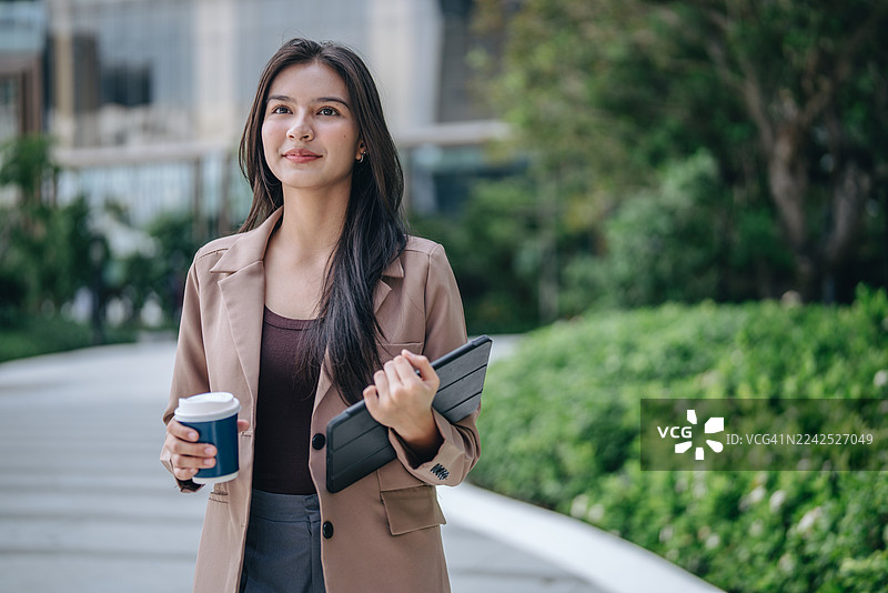 自信解放的女商人走在大都市中，一位女士拿着手机肖像图片素材