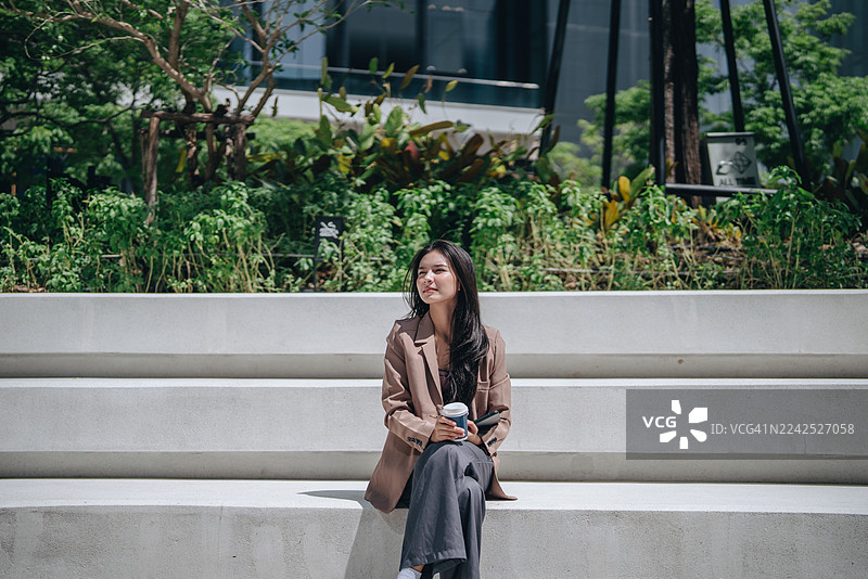 自信解放的女商人在大城市行走，一位女士拿着手机的肖像图片素材