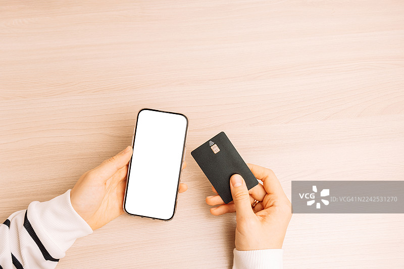 桌上，手持智能手机和银行卡图片素材