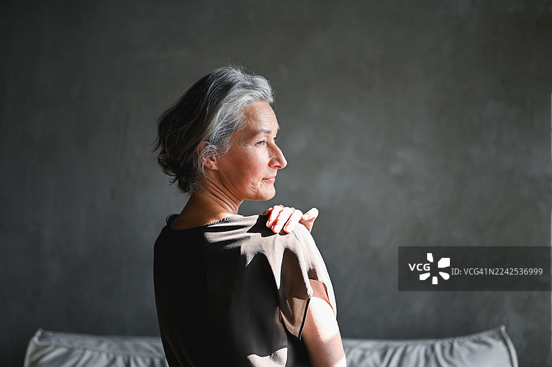 阳光照耀脸庞，一位成熟的成年女性正在沉思图片素材