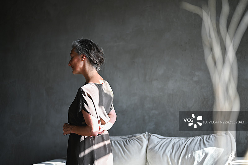 一位年长的女性在简约的城市家中沉思人生图片素材